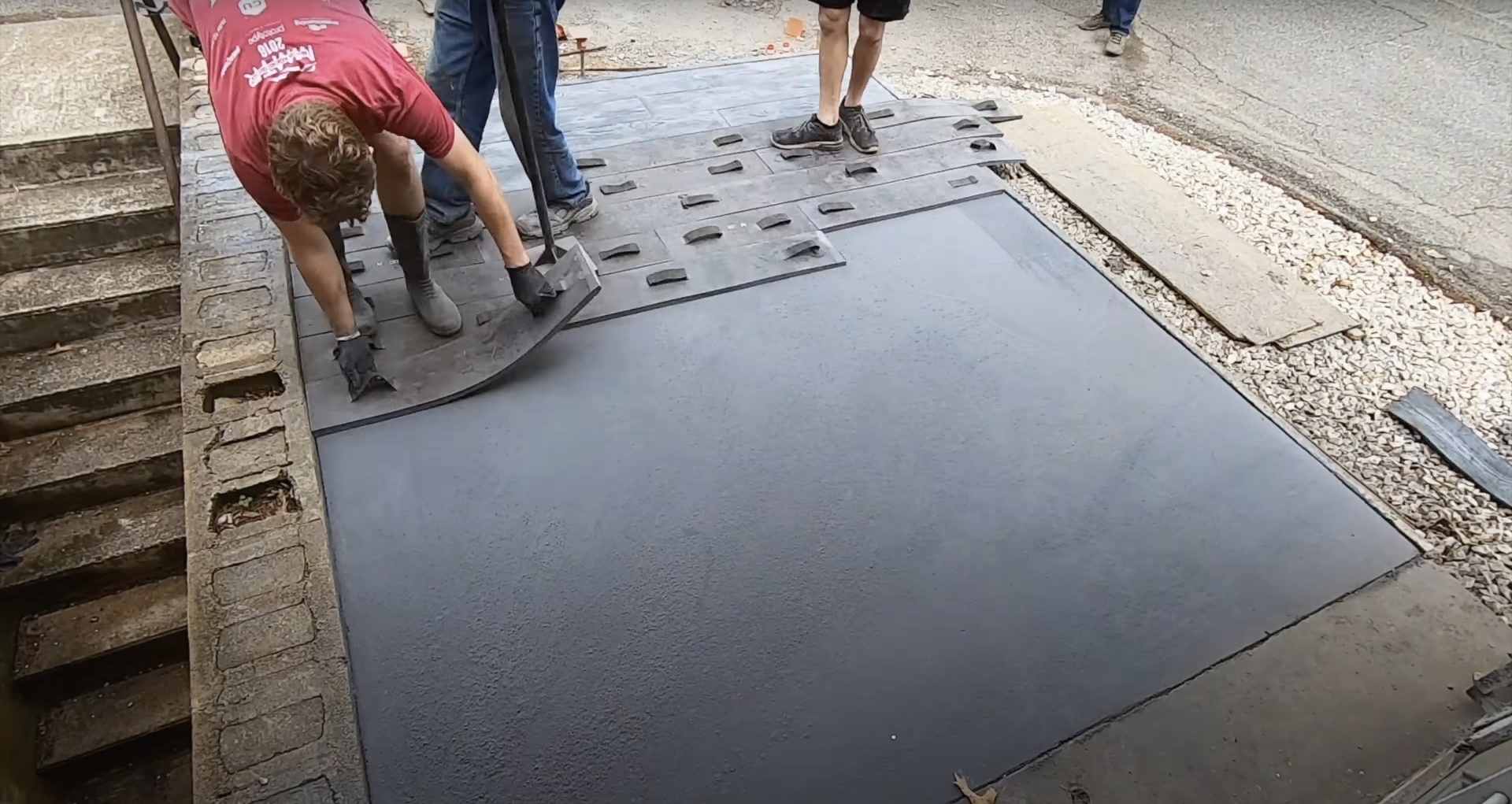 Concrete crew applying stamped texture patterns to fresh concrete surface using professional stamping tools