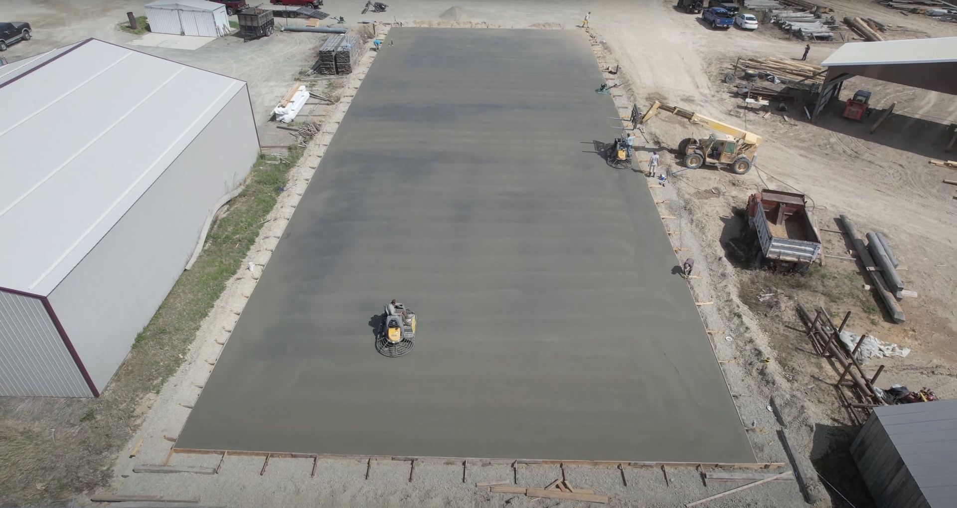 Large-scale commercial concrete slab pour with power trowel finishing equipment in operation